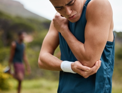 Sports man, nature and elbow pain from workout training injury or fitness running accident outdoors. Bad bruise, broken arm bone or closeup of injured athlete runner with exercise emergency in park.